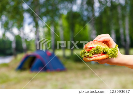 Enjoying a delicious burger at the campsite. 128993687