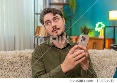 Middle-aged man annoyed sighs rolls eyes at bad smartphone message feeling frustration angry stress 128994912