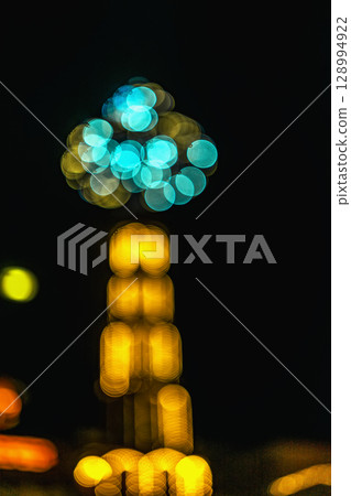 Christmas lights in defocus, abstract blurred background. Abstract bokeh lights in festive tree shape glowing in colorful tones, dark background. Concept of Christmas, holiday atmosphere 128994922