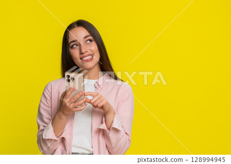 Woman typing message smartphone shyly smiling biting lip romantic emotional expression falling love Woman typing message smartphone shyly smiling biting lip romantic emotional expression falling love 128994945
