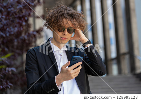 Shocked businessman using smartphone typing browsing, loses surprised by bad news fail bankruptcy 128995128