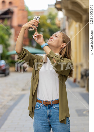 Young tourist woman trying to catch a communication signal and Internet on mobile phone on street Young tourist woman trying to catch a communication signal and Internet on mobile phone on street 128995142