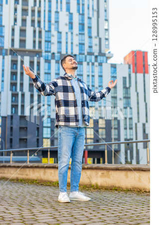 Mature man tourist with arms outstretched meditating with closed eyes standing on downtown street Mature man tourist with arms outstretched meditating with closed eyes standing on downtown street 128995153