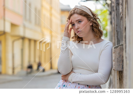 Sad unhappy frustrated young woman walking alone in city street feeling bad annoyed grief problem Sad unhappy frustrated young woman walking alone in city street feeling bad annoyed grief problem 128995163