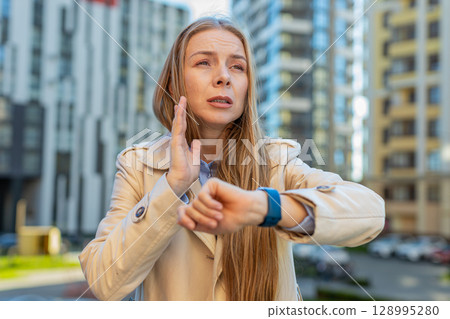 Scared businesswoman worrying to be punctual, with anxiety checking time on watch on downtown street Scared businesswoman worrying to be punctual, with anxiety checking time on watch on downtown street 128995280