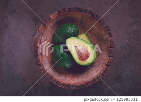 fresh, sliced avocado, in a wooden plate, top view, food background, concept, food styling 128995331