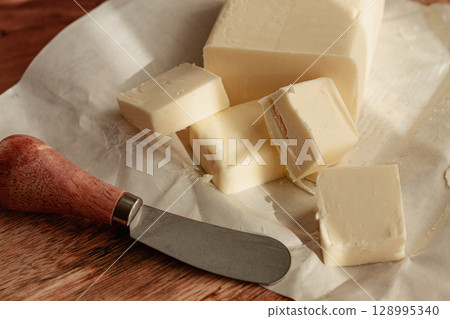 butter briquette, on wrapping paper, wooden chopping board and butter knife,breakfast, rustic style, no people, butter briquette, on wrapping paper, wooden chopping board and butter knife,breakfast, rustic style, no people, 128995340