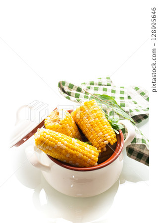 Two boiled corn cobs with dill on a white background 128995646