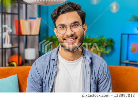 Happy Indian man smiling friendly, glad expression, feel satisfied concept good news celebrate win 128995818