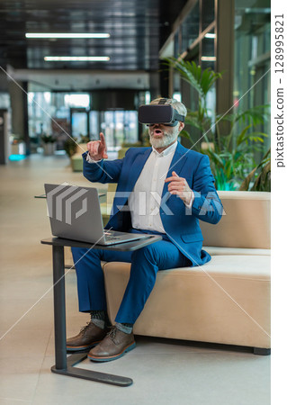 Mature businessman software developer using headset app making presentation in modern office lobby 128995821