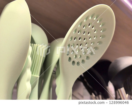 Chic green cooking utensils arranged on a shelf in a modern kitchen 128996046