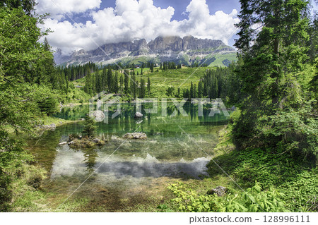 Lake Carezza reflecting the italian Dolomites on a sunny day Lake Carezza reflecting the italian Dolomites on a sunny day 128996111