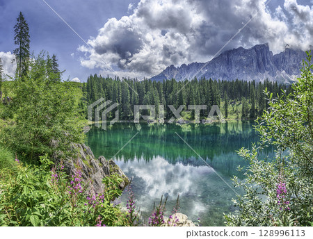 The emerald green Lake Carezza reflecting Latemar mountain, Dolomites, Italy 128996113