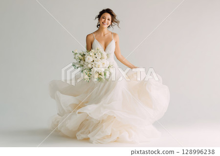 Joyful bride dances carefree in elegant white dress with bouquet in hand 128996238