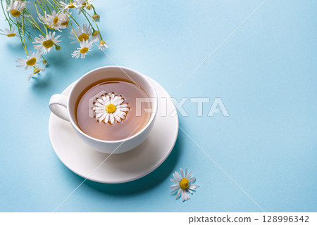 Chamomile tea cup on blue background Chamomile tea cup on blue background 128996342