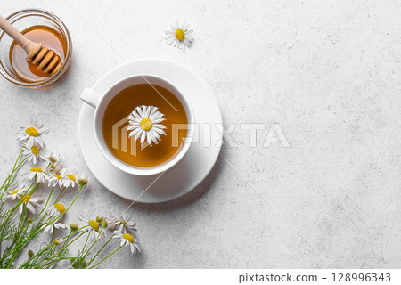 Chamomile tea cup with honey and chamomile flowers Chamomile tea cup with honey and chamomile flowers 128996343