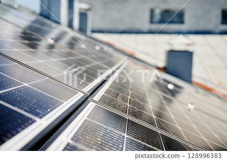 Solar photovoltaic panels on rooftop. Close up of solar batteries installed on top of modern house. Concept of alternative energy sources in modern life. Solar photovoltaic panels on rooftop. Close up of solar batteries installed on top of modern house. Concept of alternative energy sources in modern life. 128996383