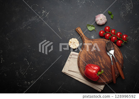 Food background with fresh vegetables and pepper mill resting on rustic wooden cutting board, black background, space for text Food background with fresh vegetables and pepper mill resting on rustic wooden cutting board, black background, space for text 128996592