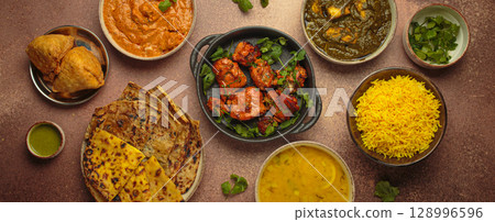 Traditional assorted Indian dishes top view on rustic brown background table. Cuisine of India 128996596