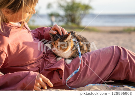 Uneasy displeased cat on owner lap petted soothed basking at beach. Nervous animal seek protection 128996908
