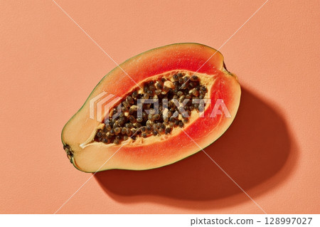 Halved Papaya with Seeds on Pastel Coral Background 128997027