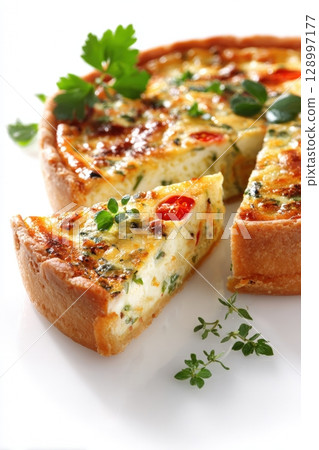 Delicious Vegetable Quiche Slice with Fresh Herbs on White Background 128997177