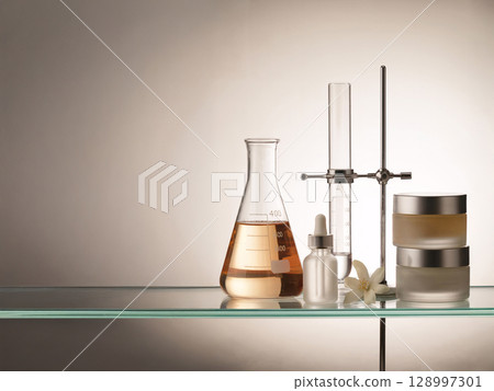 Glass skincare jars and serum dropper with lab beaker and blossom on clear shelf, combining scientific precision and natural elegance 128997301