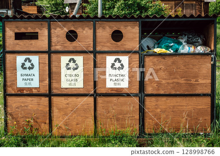 recycling bins for paper, glass, plastic located in community space in natural setting. closeup. recycling bins for paper, glass, plastic located in community space in natural setting. closeup. 128998766