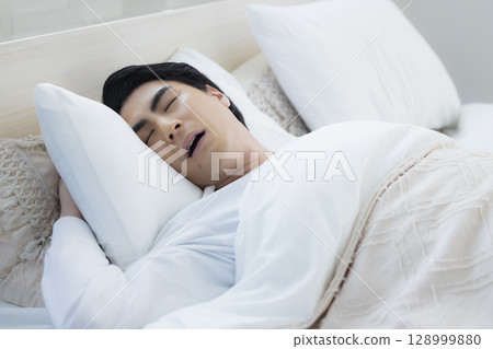 Young man sleeping in bed Young man sleeping in bed 128999880