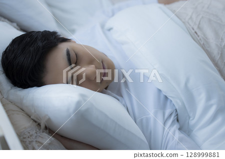 Young man sleeping in bed 128999881
