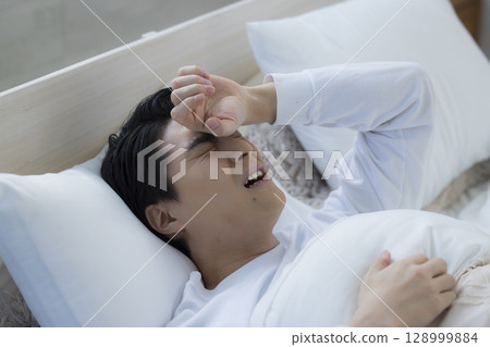 Young man sleeping in bed 128999884