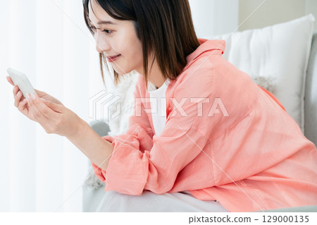 觀看在沙發的一位小姐一個智能手機 129000135