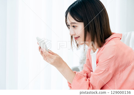 觀看在沙發的一位小姐一個智能手機 129000136