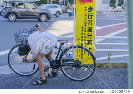 The back view of a boy peering into his bicycle 129000729