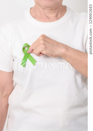 Elderly with light Green Ribbon for concept of May Celiac Awareness month, Lyme disease, September Lymphoma, Mental Health Awareness month and October Liver cancer. Health and world cancer day Elderly with light Green Ribbon for concept of May Celiac Awareness month, Lyme disease, September Lymphoma, Mental Health Awareness month and October Liver cancer. Health and world cancer day 129001683