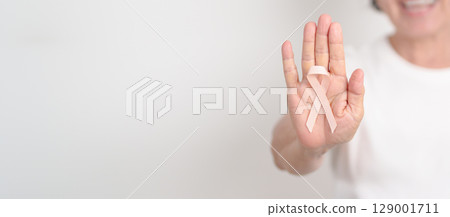 Elderly woman with Peach Ribbon for September Uterine Cancer Awareness month, Endometrial Cancer, Gynecologic, Uterus and Ovaries, Endometriosis, June Vaginal cancer and World cancer day concept 129001711