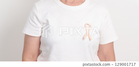 Elderly woman with Peach Ribbon for September Uterine Cancer Awareness month, Endometrial Cancer, Gynecologic, Uterus and Ovaries, Endometriosis, June Vaginal cancer and World cancer day concept 129001717