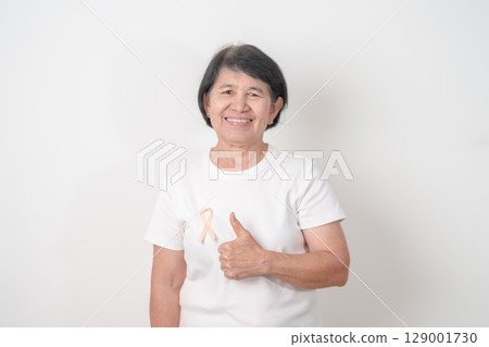 Elderly woman with Peach Ribbon for September Uterine Cancer Awareness month, Endometrial Cancer, Gynecologic, Uterus and Ovaries, Endometriosis, June Vaginal cancer and World cancer day concept 129001730
