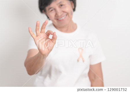 Elderly woman with Peach Ribbon for September Uterine Cancer Awareness month, Endometrial Cancer, Gynecologic, Uterus and Ovaries, Endometriosis, June Vaginal cancer and World cancer day concept 129001732