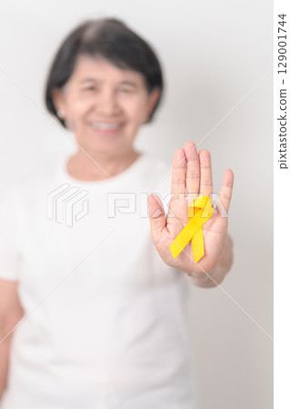Elderly with Yellow Ribbon for concept of yellow September, Suicide prevention day, Childhood, Pediatric, bone and bladder cancer Awareness month, support survivor. Healthcare and World Cancer day 129001744