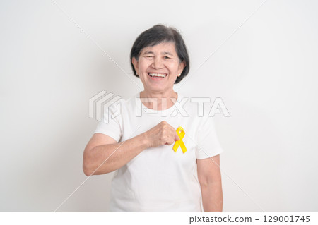 Elderly with Yellow Ribbon for concept of yellow September, Suicide prevention day, Childhood, Pediatric, bone and bladder cancer Awareness month, support survivor. Healthcare and World Cancer day 129001745
