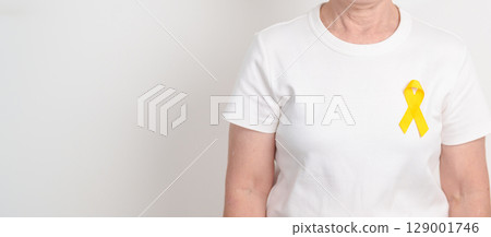 Elderly with Yellow Ribbon for concept of yellow September, Suicide prevention day, Childhood, Pediatric, bone and bladder cancer Awareness month, support survivor. Healthcare and World Cancer day 129001746