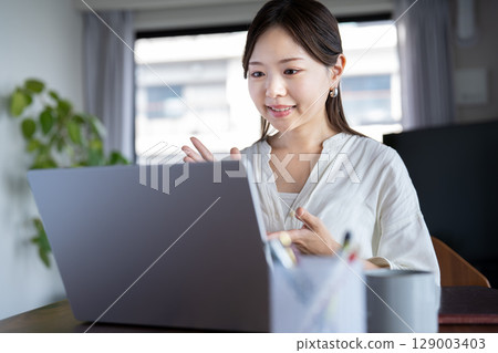 Young woman having an online meeting at home 129003403