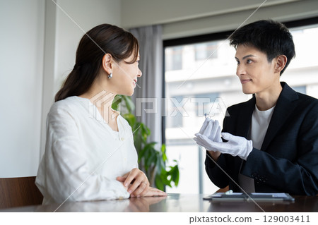 A woman receiving a jewelry appraisal and an appraiser 129003411