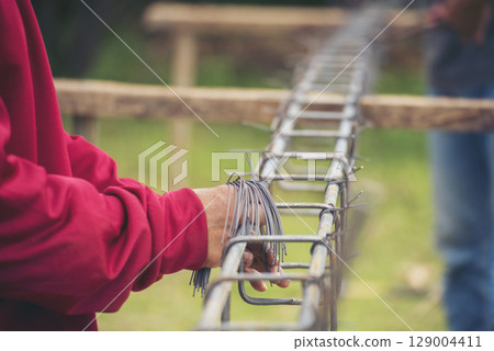 Construction Worker hands using pincer pliers iron wire. Outdoor Worker using wire bending pliers, construction work. Men hands bending cutting steel wire fences bar reinforcement of concrete work 129004411
