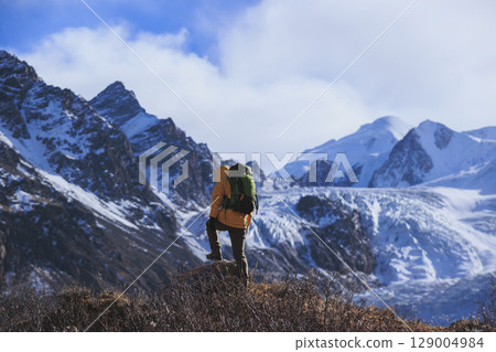 Backpacking woman hiking around the large hanging glacier on high altitude mountain top 129004984