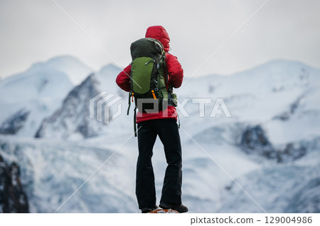 Backpacking woman hiking face a large hanging glacier on high altitude mountain top 129004986