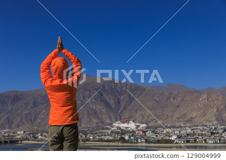 Woman praying to the potala palace in Lhasa city,Tibet,China Woman praying to the potala palace in Lhasa city,Tibet,China 129004999