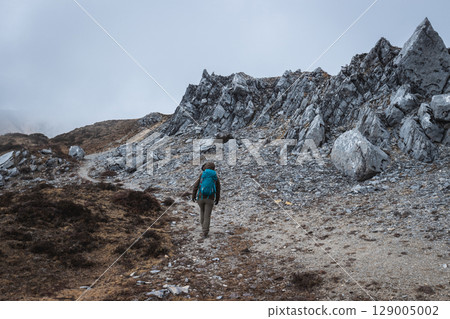 Backpacking woman hiker climbing to mountain top in tibet 129005002