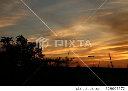 一架飛機在美麗的橙色夕陽中飛行 129005372